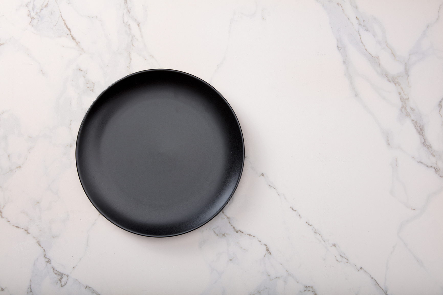 Black plate on marble kitchen countertop.